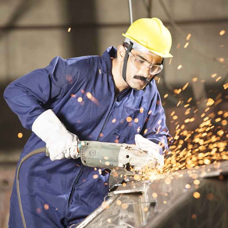 Mechanic using circular saw grinder tool with protective work wear